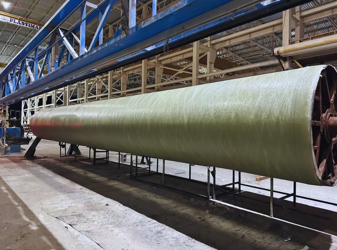 Large-diameter FRP cylindrical shell on a rotating mandrel during filament winding fabrication in an industrial shop
